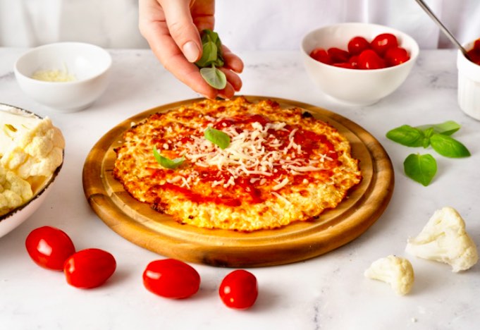 Para incluir la pizza de coliflor como parte de una dieta vegetal, reemplaza la masa de la base por una de coliflor, harina de almendras y huevo.